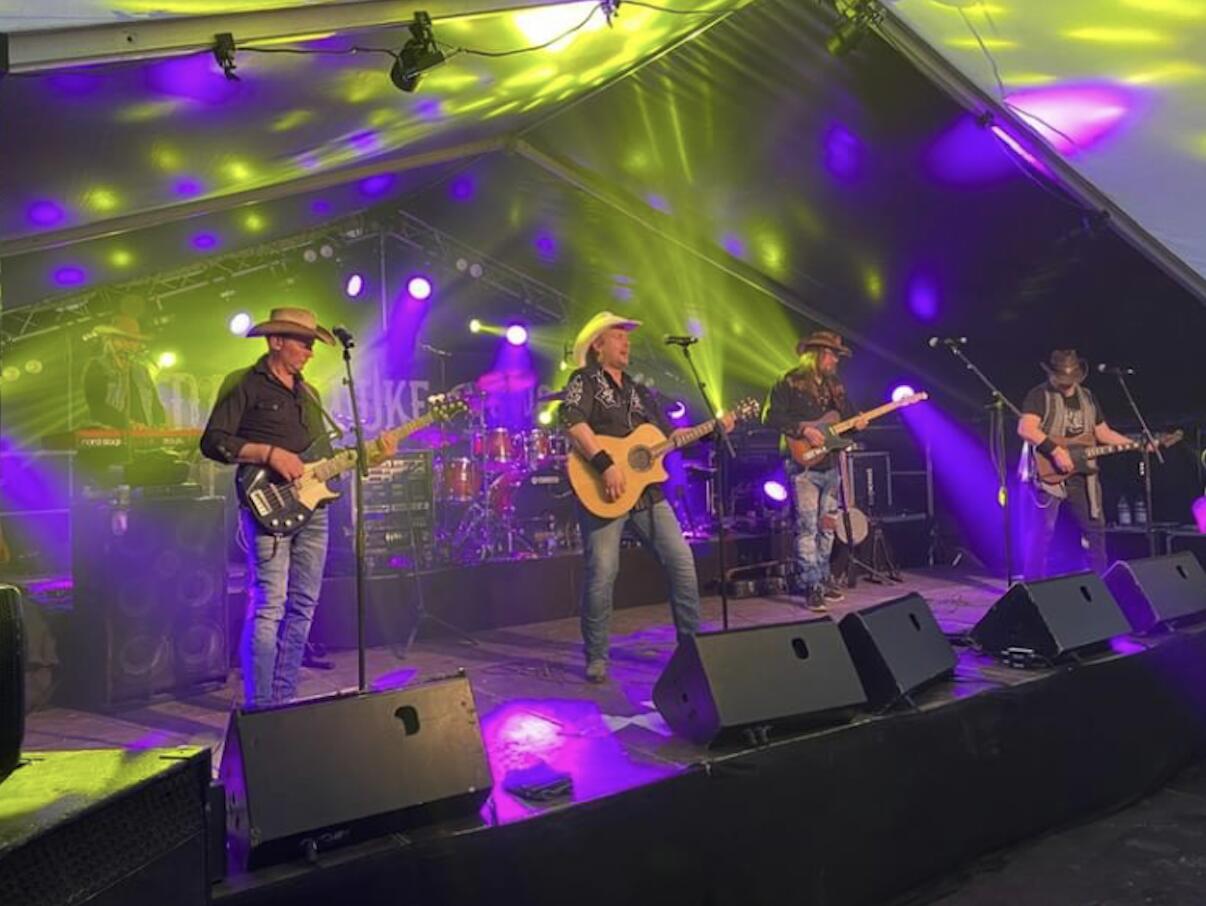Bandet live i festivaltelt med logoen bak